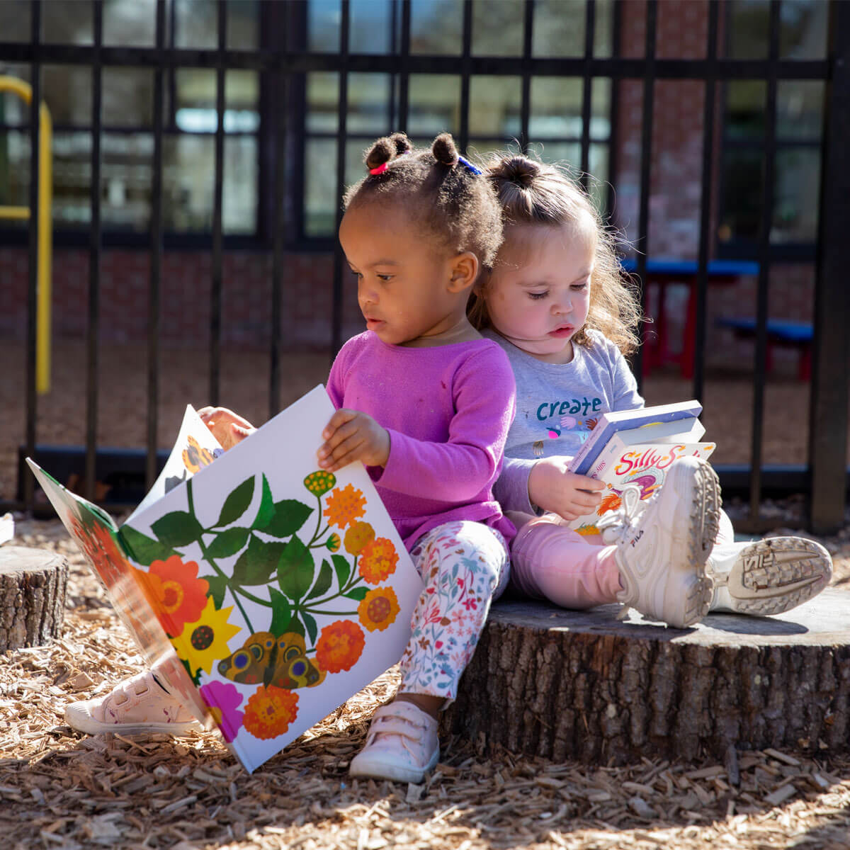 Two elementary students reading books outside.