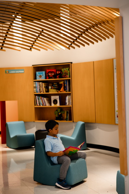 Child in a library reading to himself.